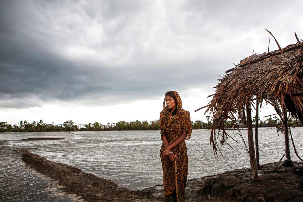 A young woman looks out over flooded land in Bangladesh. © UNFPA Bangladesh/Naymuzzaman Prince